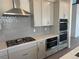A close up of a kitchen with stainless steel range and double ovens surrounded by light grey backsplash and cabinets at 9382 Quaker St, Arvada, CO 80007