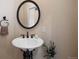 Close-up of sink with pedestal base, round mirror, decorative towel rack, and tasteful decor at 4002 Bell Mountain Dr, Castle Rock, CO 80104