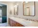 Bathroom with dual sinks, wood cabinets, tile countertops and backsplash, and decorative mirrors at 4002 Bell Mountain Dr, Castle Rock, CO 80104