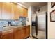 Basement wet bar featuring a sink, wood cabinets, granite countertops, and stainless steel refrigerator at 4002 Bell Mountain Dr, Castle Rock, CO 80104