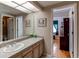 Bright bathroom featuring a vanity with a sink, a large mirror, and access to other rooms at 10291 E Powers Ave, Greenwood Village, CO 80111