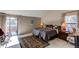 Primary bedroom with a private balcony entrance, side window, and a colorful area rug at 10291 E Powers Ave, Greenwood Village, CO 80111