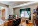 Well-lit office space with a large wooden desk, comfortable chair, and a window with green curtains at 10291 E Powers Ave, Greenwood Village, CO 80111