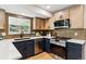 Modern kitchen featuring navy lower cabinets, quartz countertops, updated appliances, and wooden upper cabinets at 6330 E Irwin Pl, Centennial, CO 80112