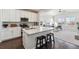 Modern kitchen featuring white cabinets, stainless steel appliances, and an island with seating, seamlessly flowing into the living area at 12597 W Big Horn Cir, Broomfield, CO 80021