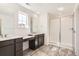 Modern bathroom featuring dual vanities with a glass enclosed walk-in shower and gray tile flooring at 4600 Thistle Dr, Brighton, CO 80601
