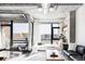 Bright living room features exposed concrete, industrial ductwork, and city views from black framed windows at 2100 16Th St # 405, Denver, CO 80202