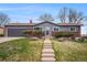 Charming ranch-style home features brick accents, a well-manicured lawn, and a concrete pathway to the front door at 12323 W Connecticut Dr, Lakewood, CO 80228