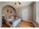 Comfortable bedroom with an arched doorway, neutral walls, hardwood floors, and a ceiling fan at 3420 Julian St, Denver, CO 80211