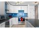 Close-up of a modernized kitchen showcasing sleek white cabinetry, blue backsplash, and stainless appliances at 1121 Albion St # 210, Denver, CO 80220