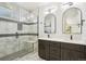 Modern bathroom with double sinks, walk-in shower with bench, and marble tiling at 3226 W Dakota Ave, Denver, CO 80219