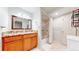 Traditional bathroom boasts wood vanity, granite countertop, shower-tub combo, and neutral color scheme at 14833 Vine St, Thornton, CO 80602