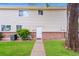 Two-story townhouse featuring neutral siding, brick accents, a well-manicured lawn, and a charming walkway to the front door at 9005 E Lehigh Ave # 16, Denver, CO 80237