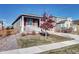 Charming single-story home with a covered porch, small tree, landscaped front yard, and attractive gray siding at 802 Eva Peak Dr, Erie, CO 80516