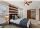 Comfortable bedroom with a ceiling fan, windows, and decoratively striped accent wall at 21258 E Aberdeen Pl, Centennial, CO 80015