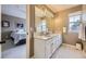 Bright bathroom with double sinks, white cabinets, and a view into the bedroom at 2522 W Dry Creek Ct, Littleton, CO 80120