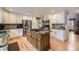 Well-equipped kitchen featuring white cabinetry, stainless steel appliances, and a large island with cooktop at 2522 W Dry Creek Ct, Littleton, CO 80120