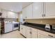 Bright laundry room with white cabinetry, dark countertops, and a full-sized washer and dryer at 2522 W Dry Creek Ct, Littleton, CO 80120