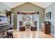 Bright living room with elegant furnishings, including a vintage piano, bay windows and comfortable chairs at 2522 W Dry Creek Ct, Littleton, CO 80120