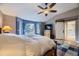 Comfortable main bedroom featuring hardwood floors, a ceiling fan, and a bay window overlooking a snowy scene at 2522 W Dry Creek Ct, Littleton, CO 80120