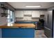 Well-lit kitchen with modern appliances, white cabinets, and stylish blue island at 5063 W 61St Ave, Arvada, CO 80003