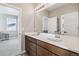 Bright bathroom featuring a double vanity, modern fixtures, and a large mirror reflecting the bedroom beyond at 16075 E 109Th Pl, Commerce City, CO 80022