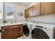 Functional laundry room with modern washer and dryer, wooden cabinets, and ample counter space at 16075 E 109Th Pl, Commerce City, CO 80022