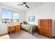 Bright bedroom featuring a ceiling fan, large window, wooden desk, and matching wooden dresser at 9567 Juniper Way, Arvada, CO 80007