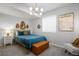 Stylish bedroom featuring a modern chandelier, a teal bed with a storage bench, and a gray accent chair at 9567 Juniper Way, Arvada, CO 80007