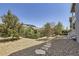 Backyard featuring mature landscaping, stone pathway, and view of the home at 12685 W Montane Dr, Broomfield, CO 80021