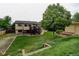 Exterior of home featuring a wooden deck and a spacious backyard with green grass and sheds at 9766 Fillmore St, Thornton, CO 80229