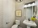 Stylish powder room with designer wallpaper, pedestal sink, and modern lighting at 4585 Mesa Top Dr, Monument, CO 80132
