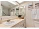 Bright bathroom featuring a single sink vanity, neutral paint, and framed mirror with tub and shower in the background at 12172 Melody Dr # 102, Denver, CO 80234