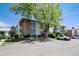 Multi-level apartment complex with beige siding and red brick under a bright blue sky with mature trees at 12172 Melody Dr # 102, Denver, CO 80234