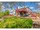 Exterior view of backyard featuring a deck, patio, mature trees, and green grass at 16222 E Prentice Ln, Centennial, CO 80015