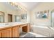Bathroom with double sinks, wooden cabinets, white tile, and large mirror with vanity lighting at 16222 E Prentice Ln, Centennial, CO 80015