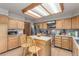 Bright kitchen featuring a central island with seating, light wood cabinets, and modern appliances at 16222 E Prentice Ln, Centennial, CO 80015