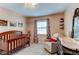 Bedroom with a wooden crib, comfy chair, and changing table, perfect for a new baby at 6111 W Maplewood Pl, Littleton, CO 80123