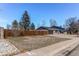 Charming exterior of a home featuring a well-maintained lawn, mature trees, a private yard, and a paved driveway at 6111 W Maplewood Pl, Littleton, CO 80123