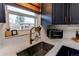 Close up of kitchen features farmhouse sink, custom faucet, open shelving and view to back yard at 6111 W Maplewood Pl, Littleton, CO 80123