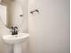 Modern powder room with pedestal sink, round mirror and black hardware at 2670 E 102Nd Pl, Thornton, CO 80229