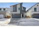 Modern two-story home with gray siding, a gray garage door, and a concrete driveway partially covered in snow at 19088 E 94Th Pl, Commerce City, CO 80022