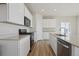 Modern kitchen with stainless appliances, white cabinets, stone counters and wood-look flooring at 19088 E 94Th Pl, Commerce City, CO 80022