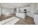 Bright living room and kitchen with white cabinets, stainless appliances, wood floors, and modern design at 19088 E 94Th Pl, Commerce City, CO 80022