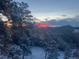 Beautiful mountain view overlooking snow-covered trees and a glimpse of a colorful sunset at 5396 Bear Mountain, Evergreen, CO 80439