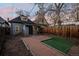 Cozy backyard featuring a brick patio, artificial grass and access to a charming detached garage at dusk at 374 S Lincoln St, Denver, CO 80209