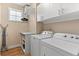 Functional laundry room with modern washer, dryer, shelving, and window at 2429 S Orchard St, Lakewood, CO 80228