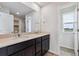 Modern bathroom with dual sinks, quartz countertop, dark cabinets, and views of a front yard at 14400 Heritage Dr, Mead, CO 80504
