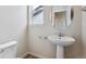 Elegant half-bathroom with a pedestal sink, round mirror, and modern fixtures at 14400 Heritage Dr, Mead, CO 80504
