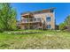 Exterior rear view of two-story home with large wooden deck, big yard, and lovely landscaping at 1905 Graphite Ct, Castle Rock, CO 80108